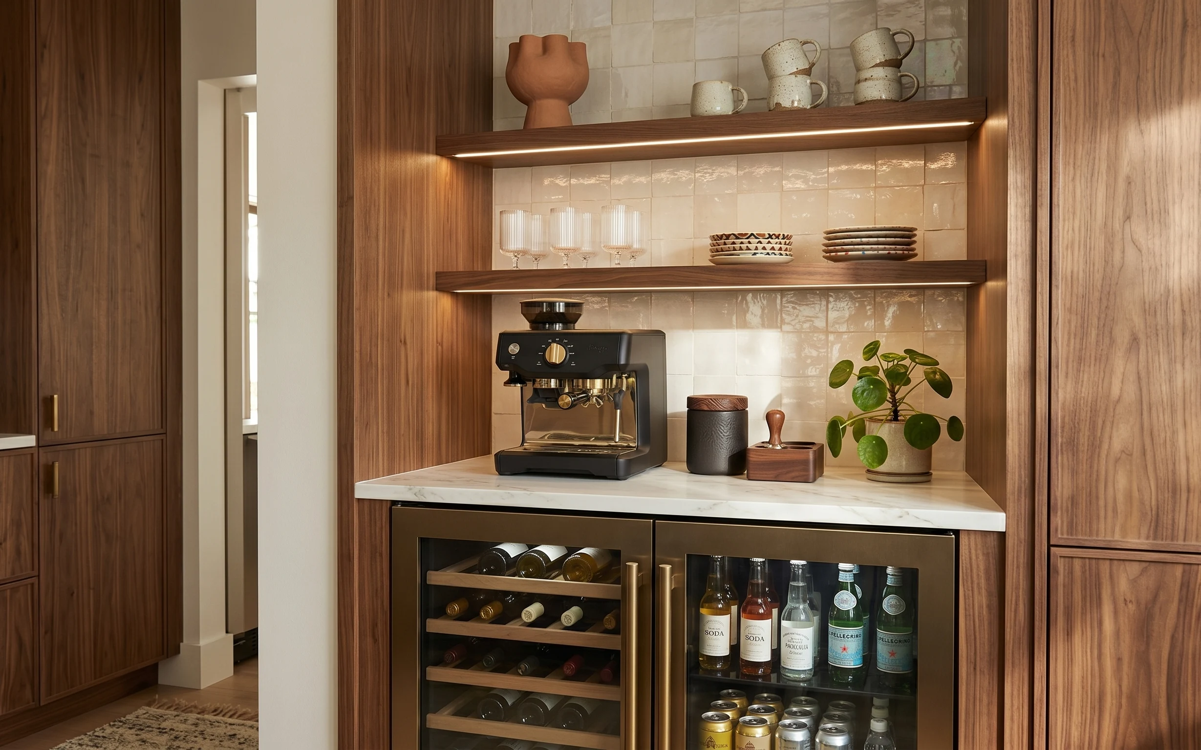Warm wood-and-tile kitchen coffee nook with marble counter, ceramic mugs, potted plant, and wine fridge bottles